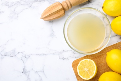 Flat lay composition with freshly squeezed lemon juice on white marble table. Space for text