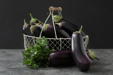 Photo of Ripe purple eggplants and parsley on grey table