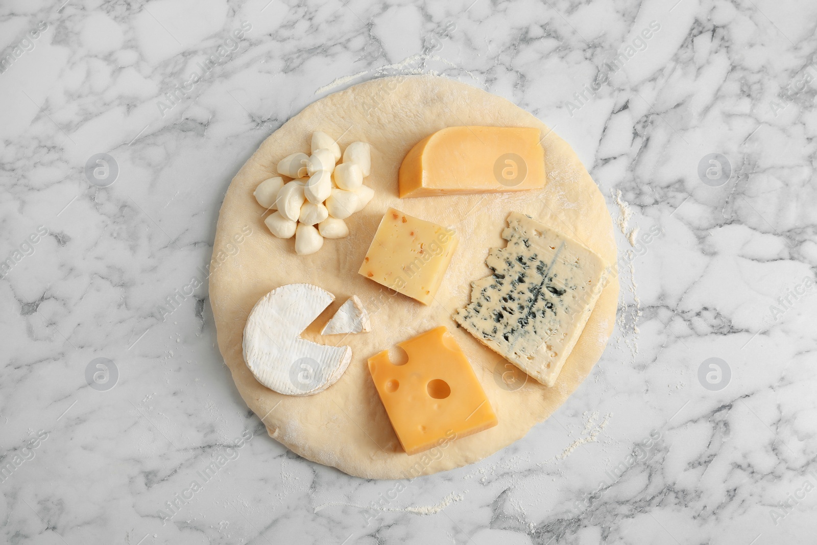 Photo of Pizza crust with fresh ingredients on marble table, top view