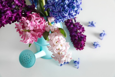 Photo of Beautiful hyacinths in watering can on table, closeup. Spring flowers