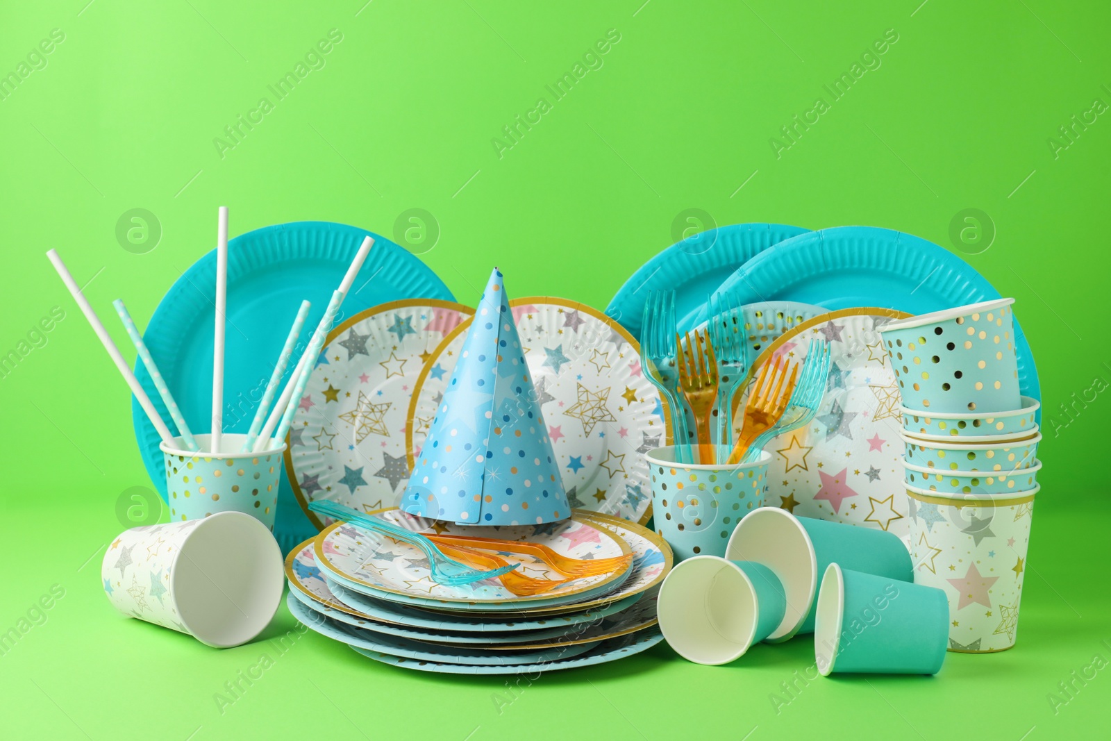 Photo of Set of disposable tableware on green background
