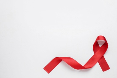Photo of Top view of red ribbon on white background, space for text. AIDS disease awareness