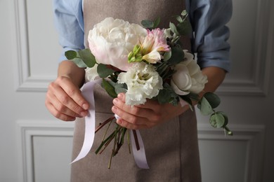 Photo of Florist creating beautiful bouquet at white wall, closeup