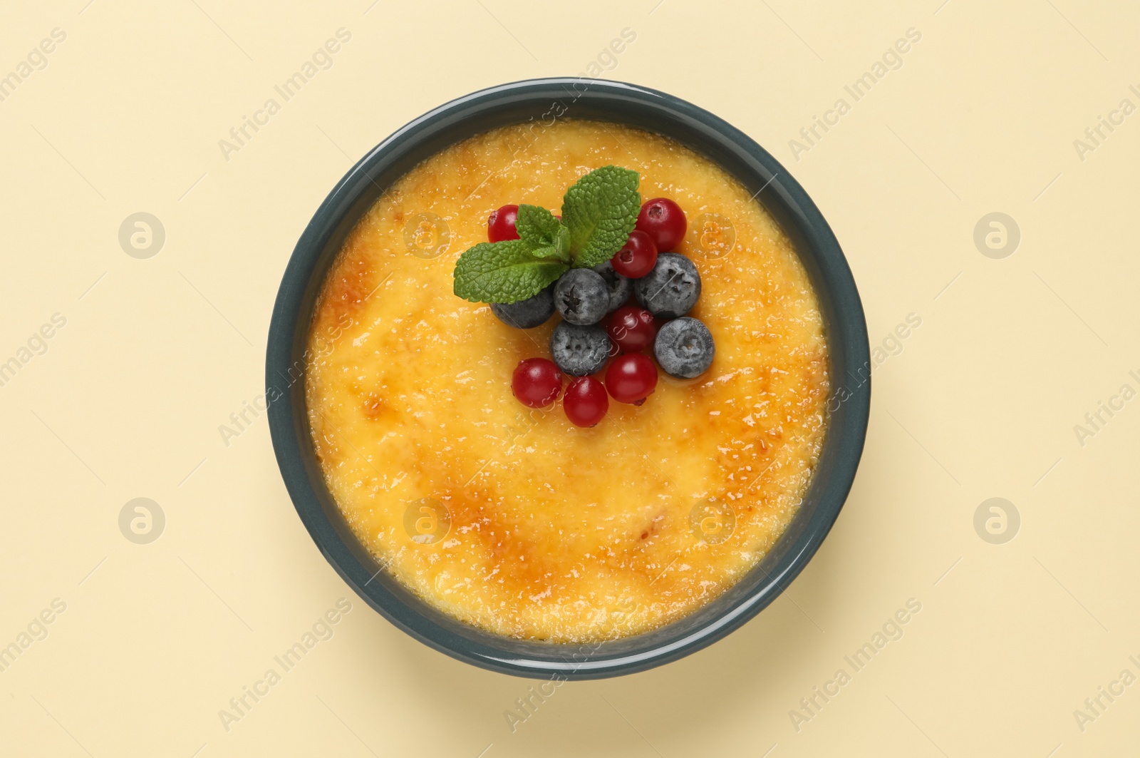 Photo of Delicious creme brulee with fresh berries on beige background, top view