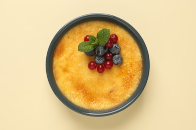 Delicious creme brulee with fresh berries on beige background, top view