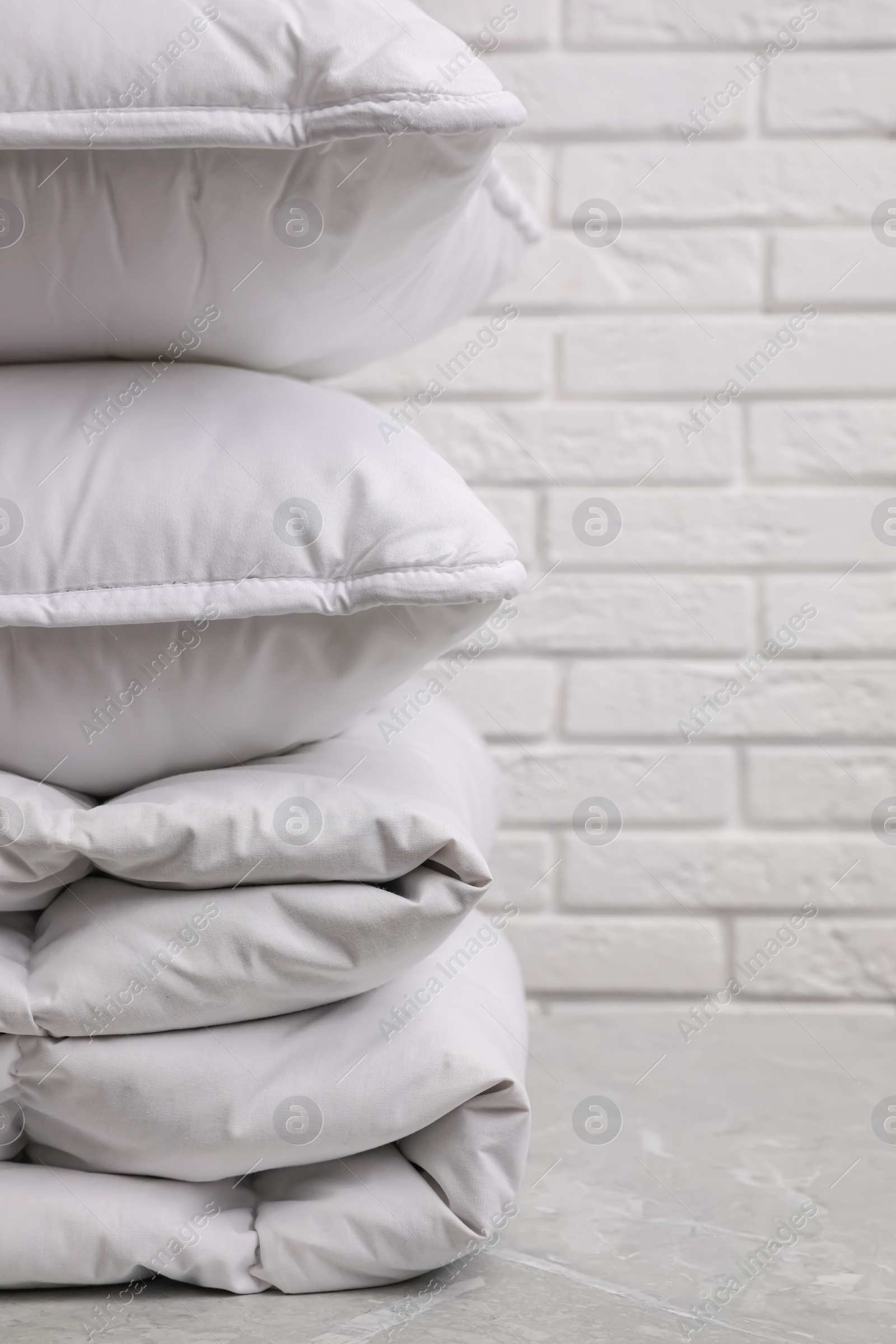 Photo of Soft folded blanket and pillows on light grey table, closeup