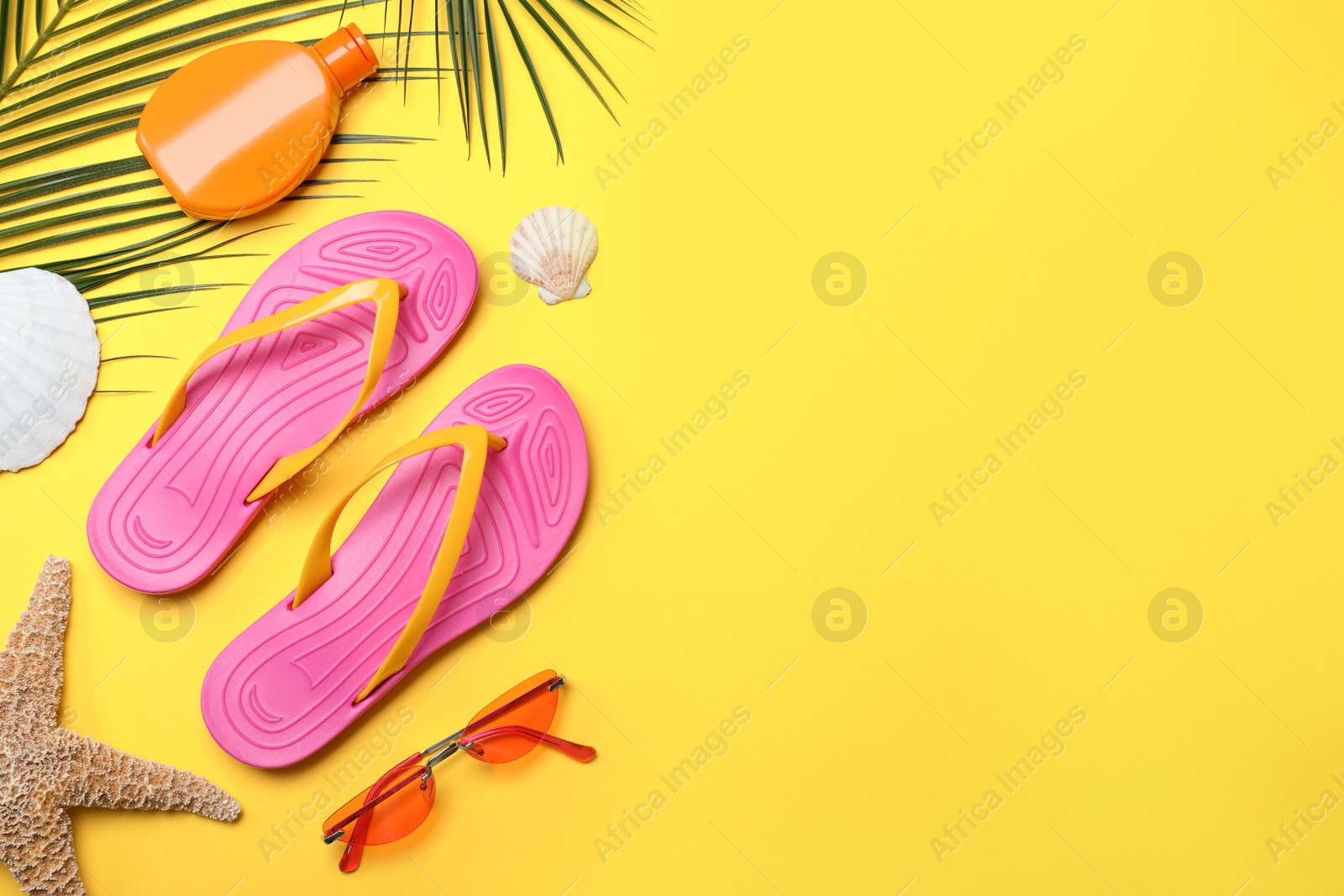 Photo of Stylish flip flops and beach objects on yellow background, flat lay. Space for text