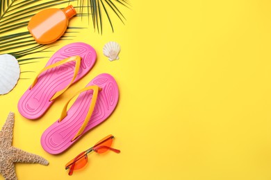 Stylish flip flops and beach objects on yellow background, flat lay. Space for text