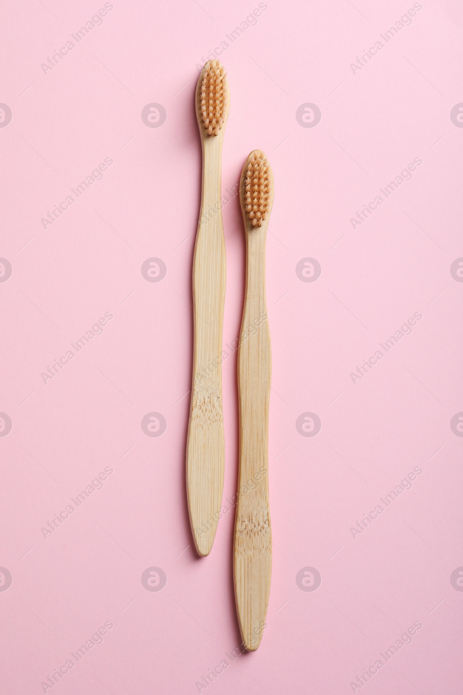 Photo of Two bamboo toothbrushes on pink background, flat lay