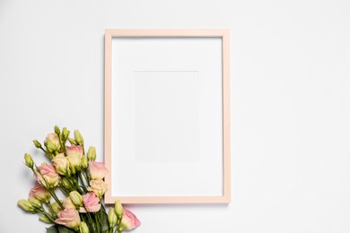 Photo of Empty photo frame and beautiful flowers on white background, top view. Space for design