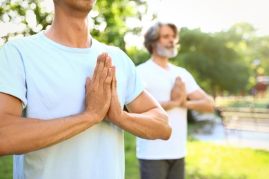 Men practicing morning yoga in sunny park, closeup