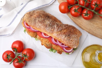 Photo of Delicious sandwich with schnitzel on white tiled table, flat lay