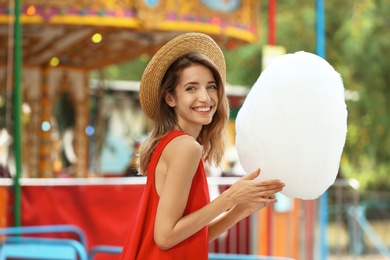 Happy young woman with cotton candy in amusement park