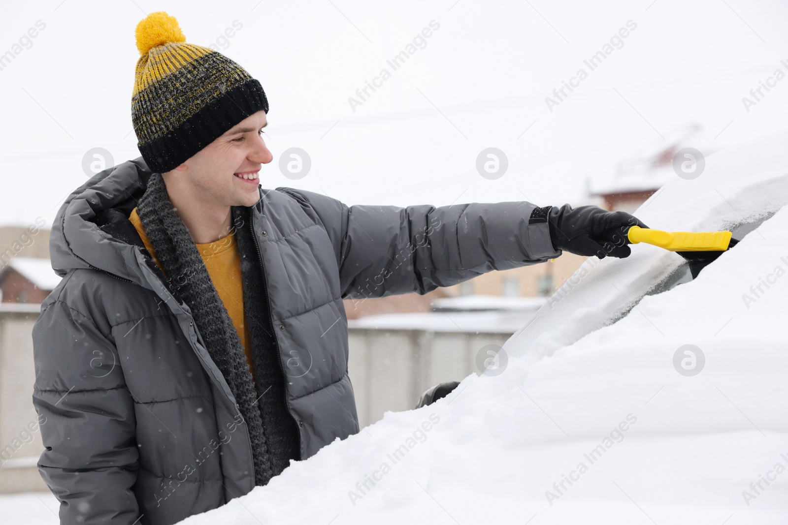 Photo of Man cleaning snow from car windshield outdoors