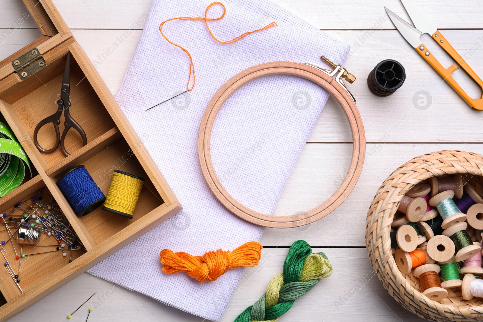 Photo of Set of embroidery equipment on white wooden table, flat lay