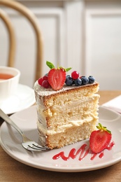 Photo of Piece of delicious homemade cake with fresh berries served on wooden table