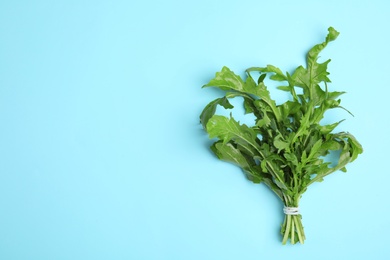 Photo of Fresh arugula on light blue background, top view. Space for text