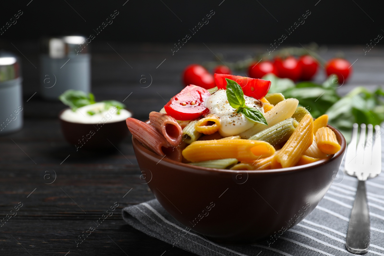 Photo of Delicious vegetable pasta with sour cream dressing on black wooden table