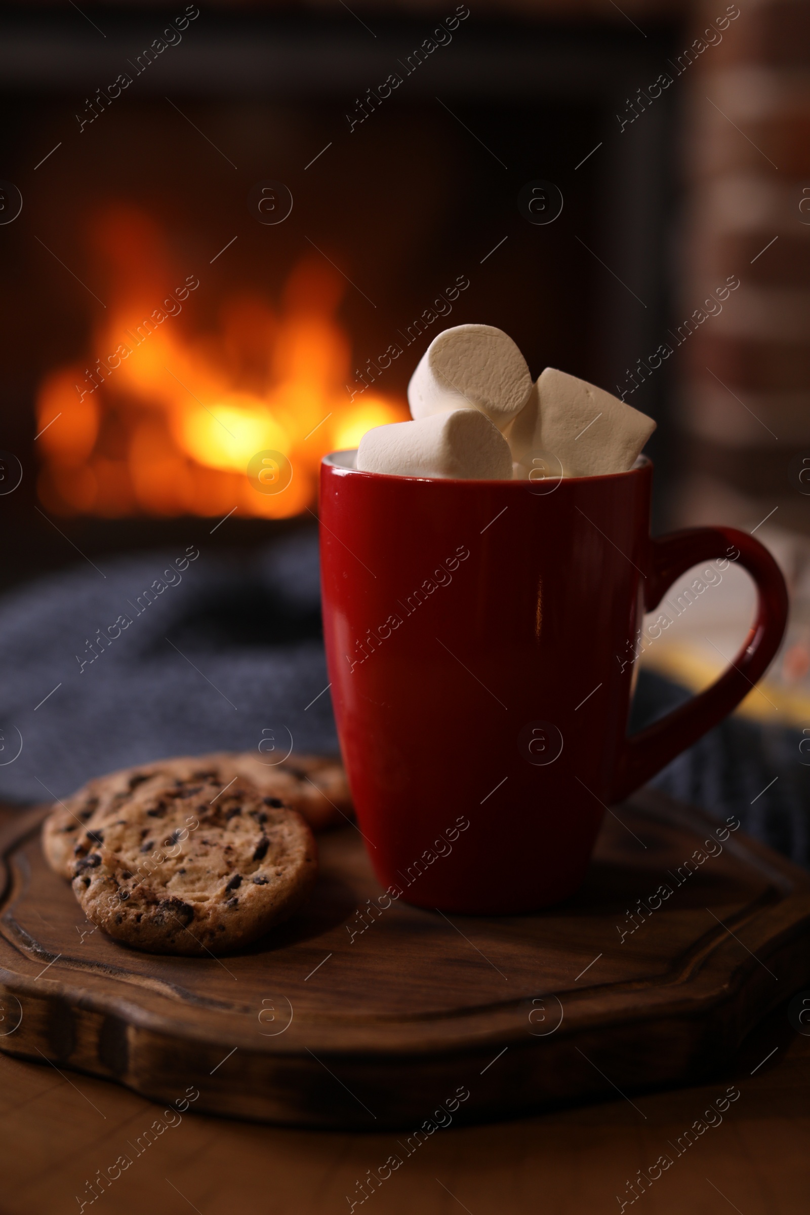 Photo of Delicious sweet cocoa with marshmallows, cookies and blurred fireplace on background