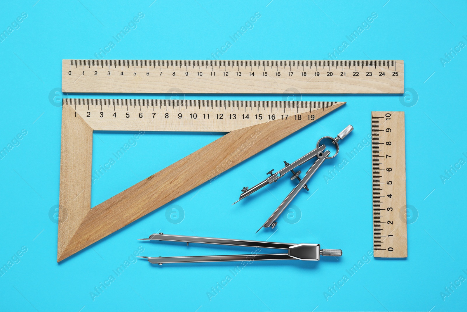 Photo of Different rulers and compass on light blue background, flat lay