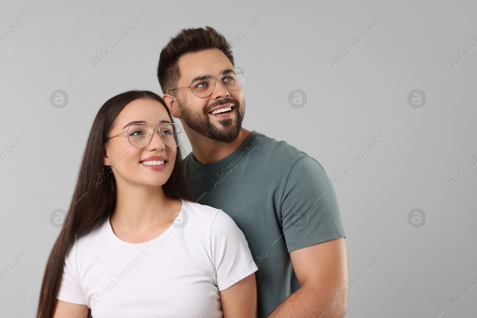 Photo of Beautiful couple wearing glasses on light gray background, space for text
