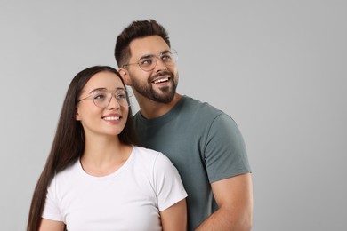 Beautiful couple wearing glasses on light gray background, space for text