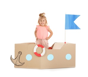 Cute little girl playing with cardboard ship on white background