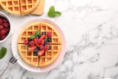 Photo of Tasty Belgian waffles with fresh berries served on white marble table, flat lay. Space for text