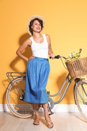 Portrait of beautiful young woman with bicycle near color wall