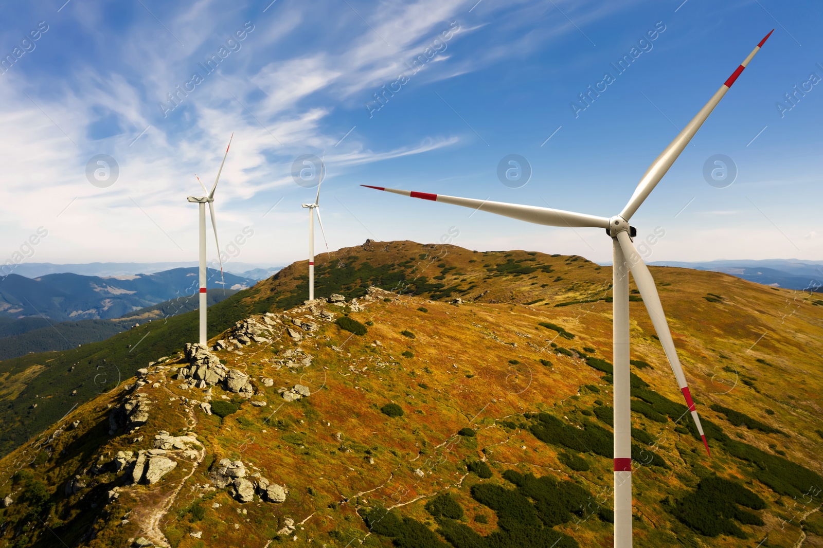 Image of Modern wind turbines in mountains on sunny day. Alternative energy source