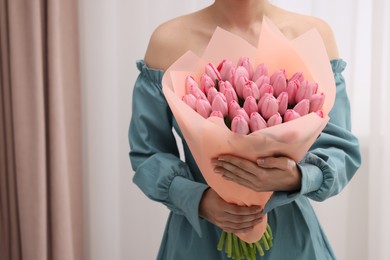 Woman holding bouquet of pink tulips indoors, closeup