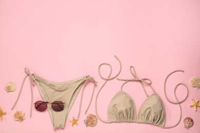 Photo of Stylish bikini, sunglasses, starfishes and shells on pink background, flat lay. Space for text