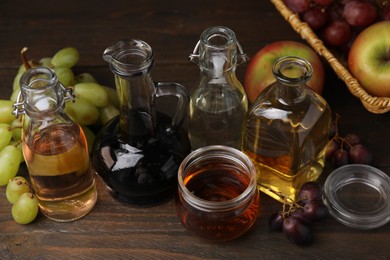 Different types of vinegar and fresh fruits on wooden table