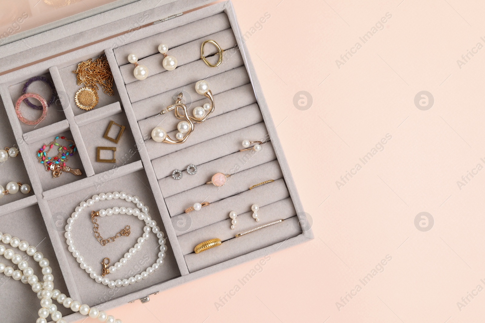 Photo of Jewelry box with many different accessories on beige background, top view. Space for text