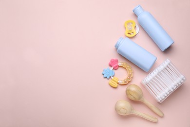 Photo of Different skin care products for baby, cotton buds, rattles and pacifier on light coral background, flat lay. Space for text