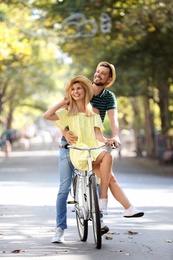 Photo of Happy couple riding bicycle together on street