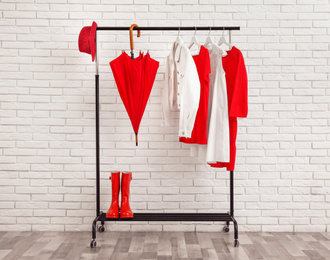 Photo of Rack with stylish clothes near white brick wall