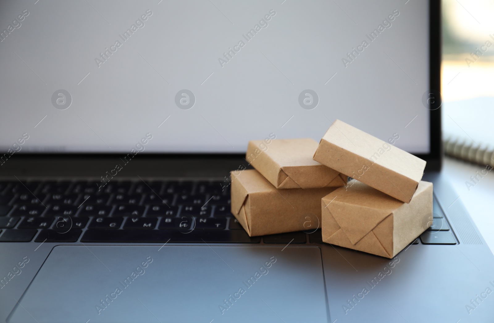 Photo of Internet shopping. Small boxes on modern laptop, space for text