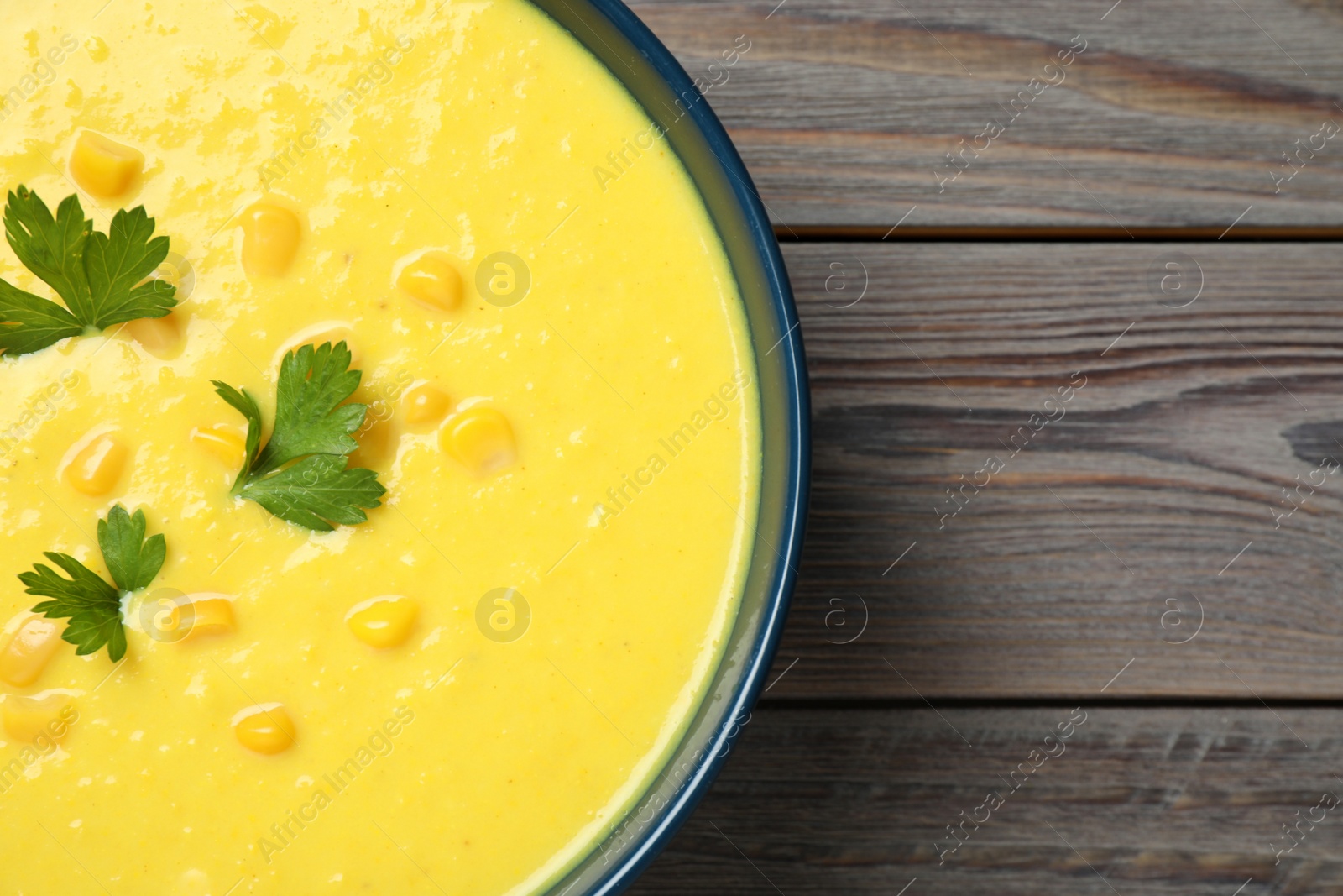 Photo of Delicious creamy corn soup served on wooden table, top view