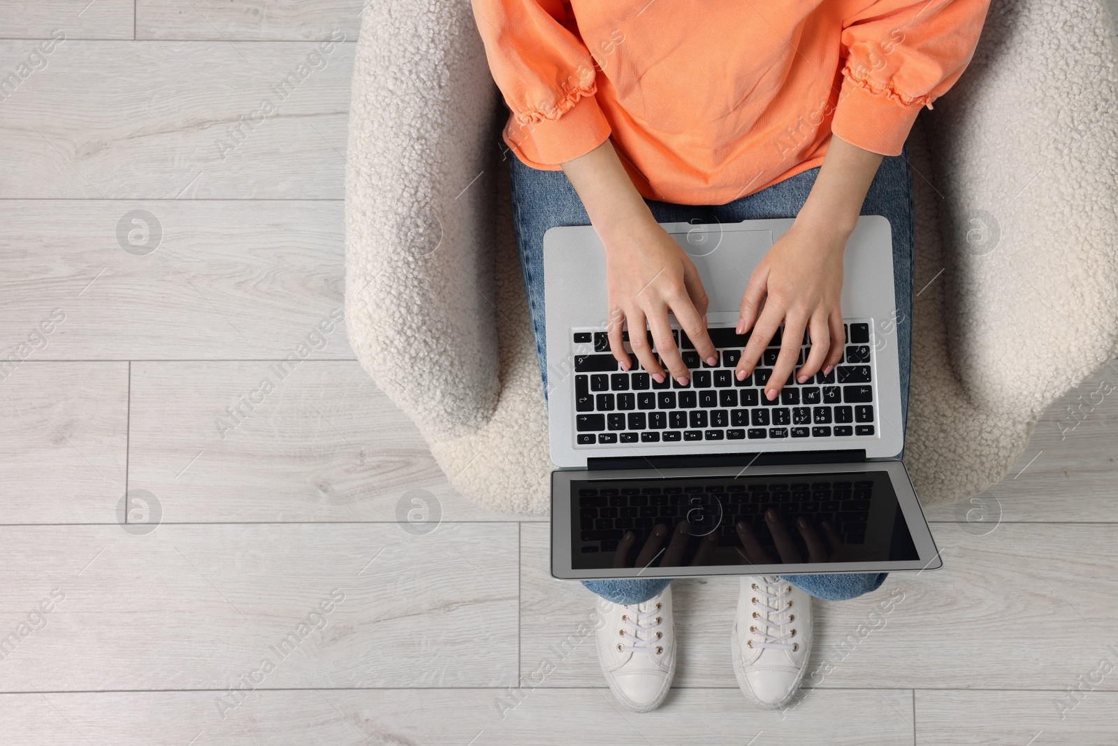 Photo of Woman working with laptop in armchair, top view. Space for text