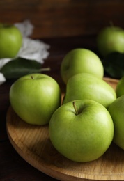 Photo of Fresh ripe green apples on wooden tray, closeup