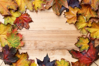 Frame made of autumn leaves on wooden background, top view. Space for text