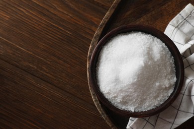 Organic salt in bowl on wooden table, top view. Space for text