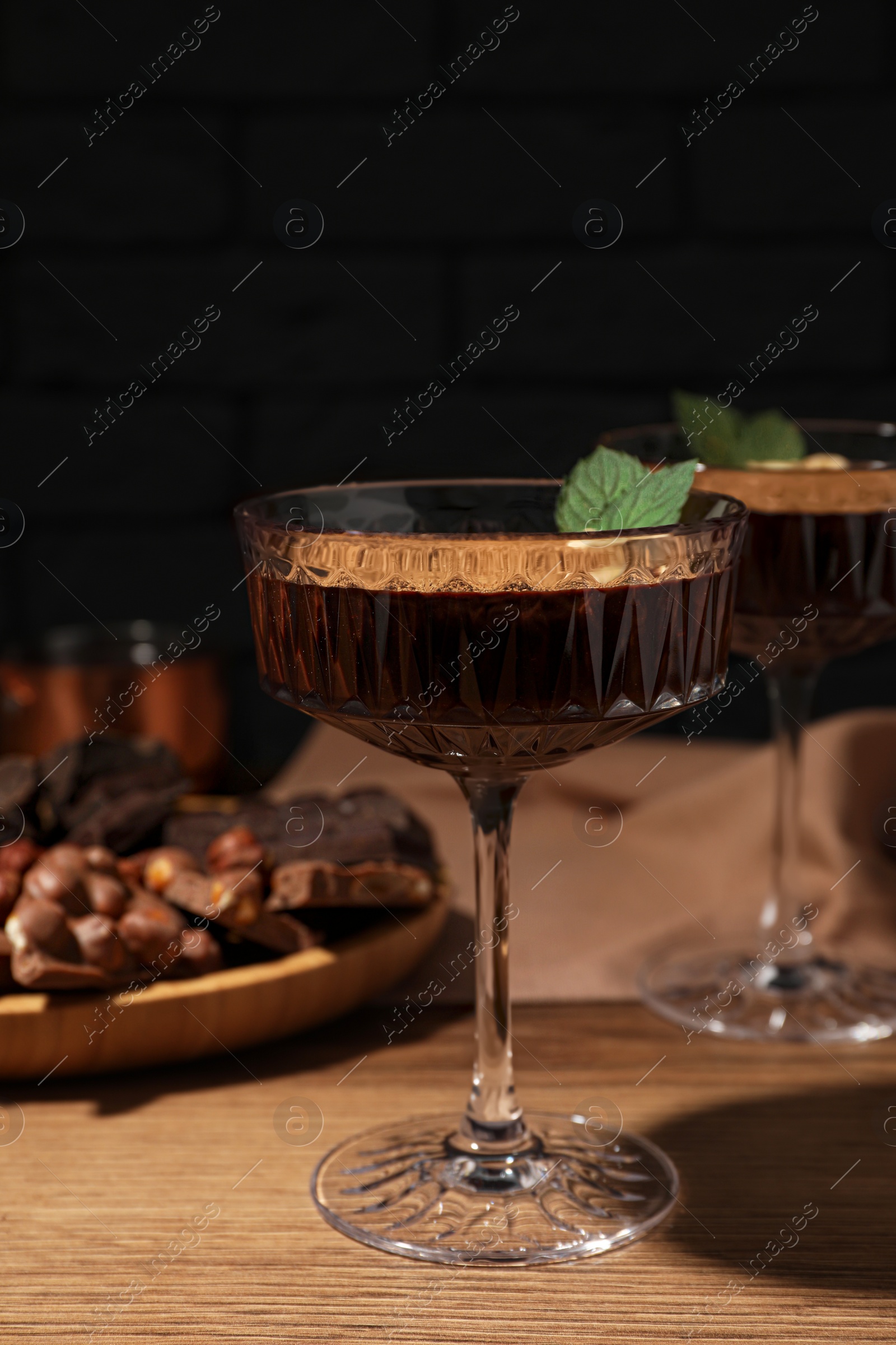 Photo of Dessert bowls of delicious hot chocolate and ingredients on wooden table, closeup