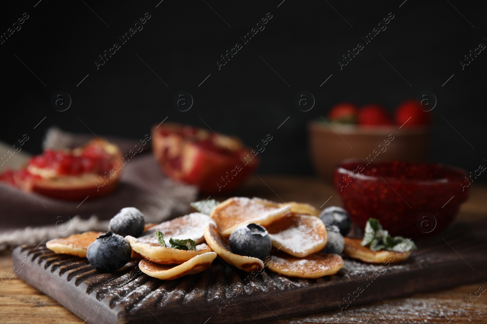 Photo of Cereal pancakes with blueberries and powdered sugar on wooden table, closeup