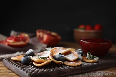 Photo of Cereal pancakes with blueberries and powdered sugar on wooden table, closeup