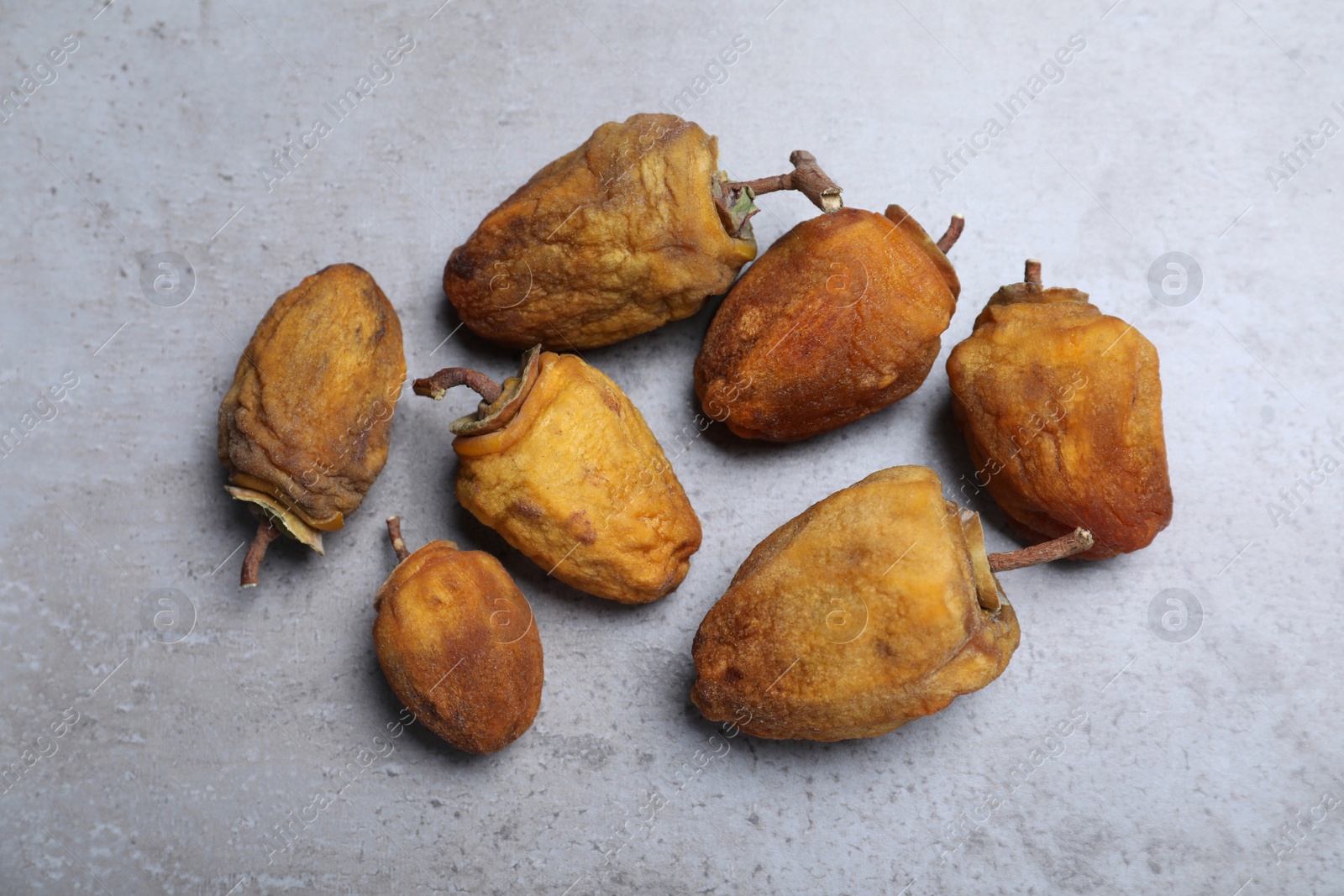 Photo of Many tasty dried persimmon fruits on light grey table, flat lay