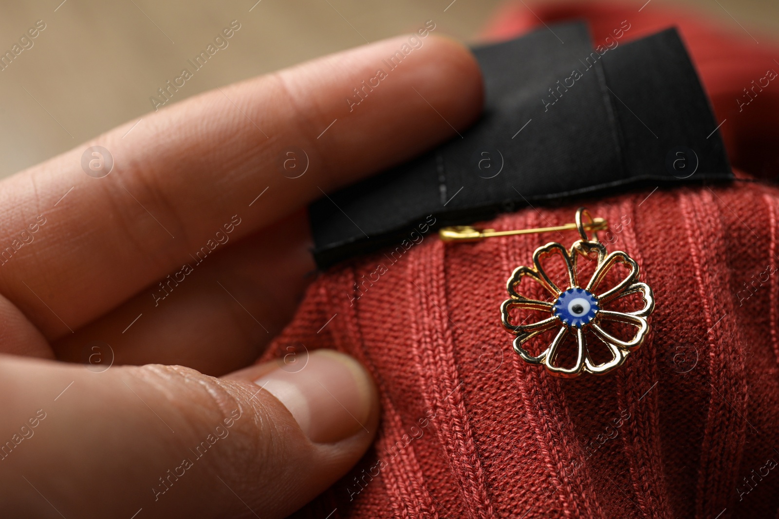 Photo of Woman holding clothing with evil eye safety pin, closeup