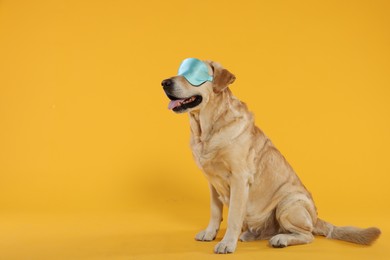 Cute Labrador Retriever with sleep mask on yellow background, space for text