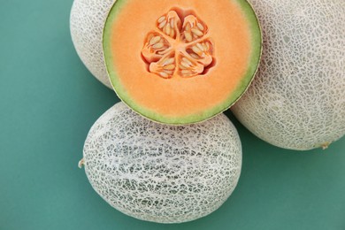 Whole and cut fresh ripe cantaloupe melons on teal background, flat lay